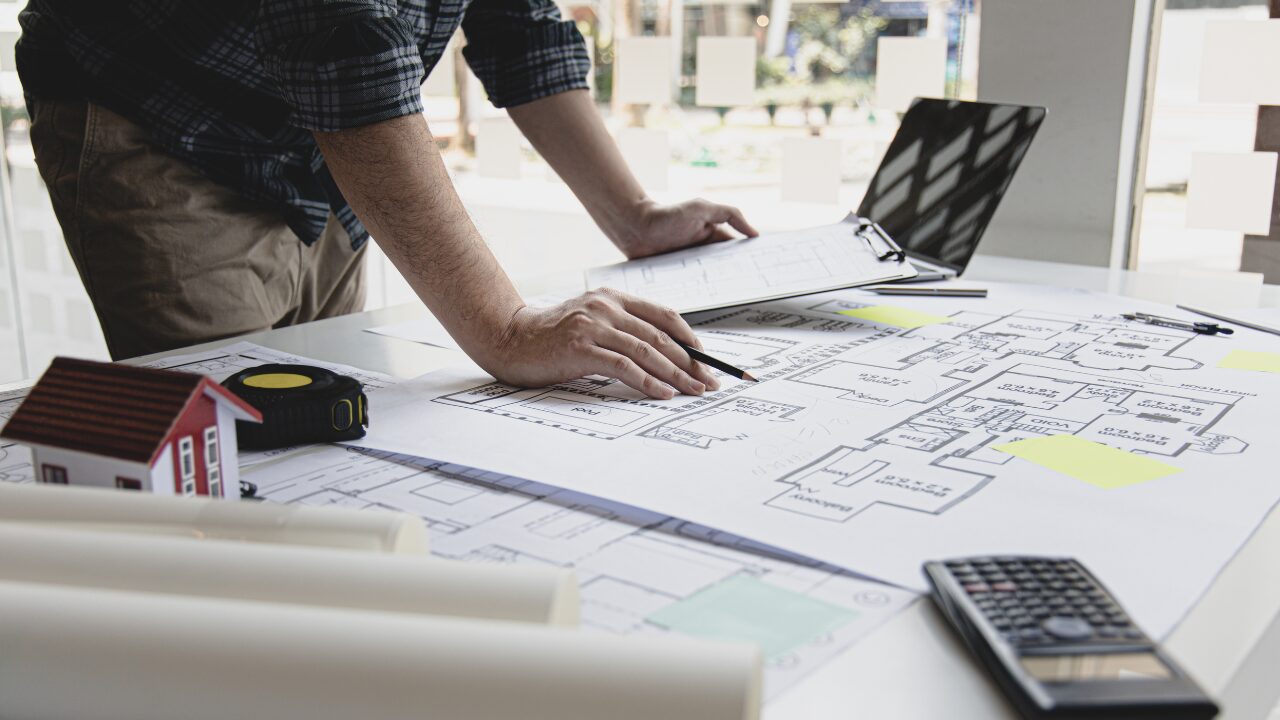 Draughtsman reviewing architectural drawings with pencils